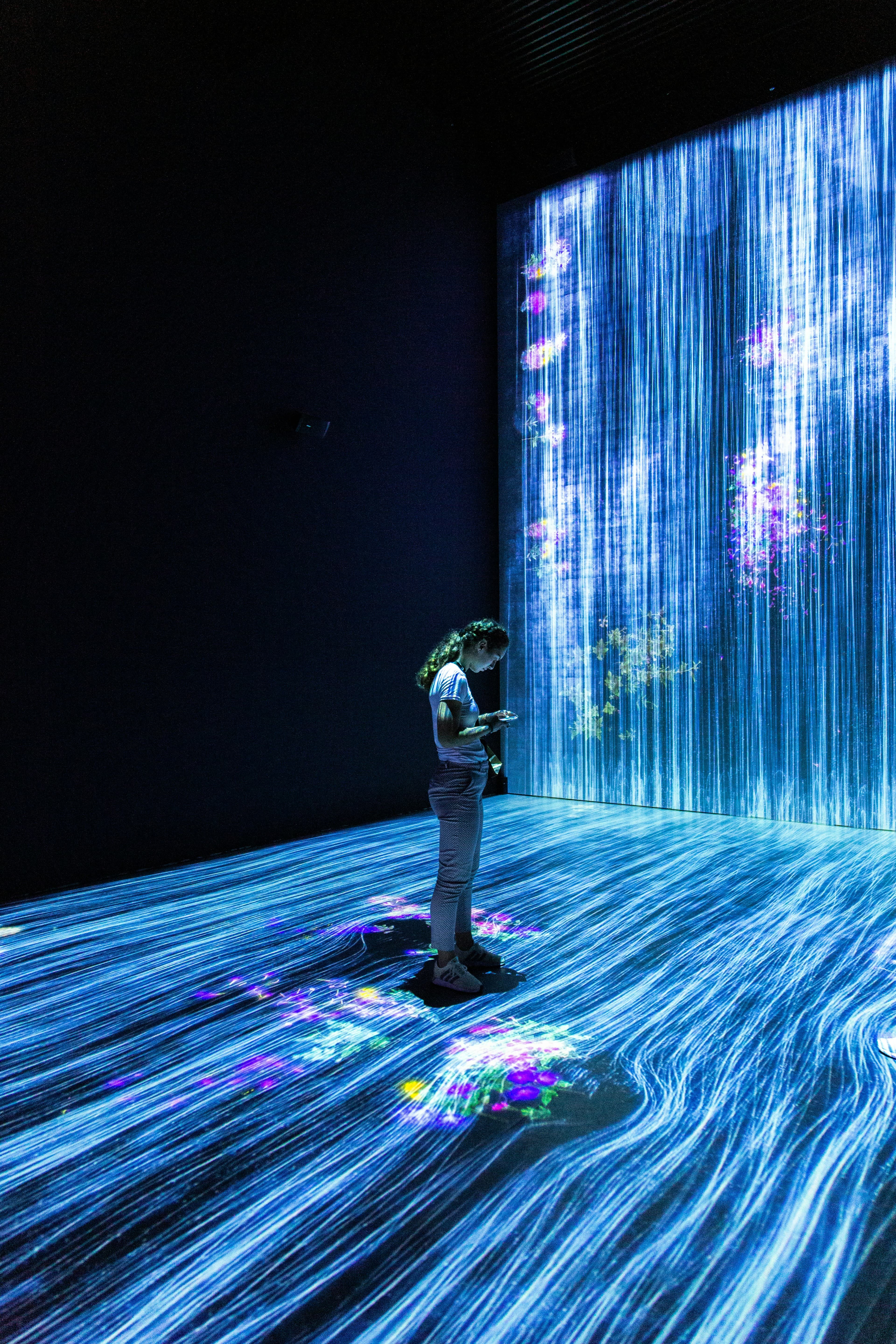 Person standing amid immersive blue digital light streams, representing cybersecurity monitoring